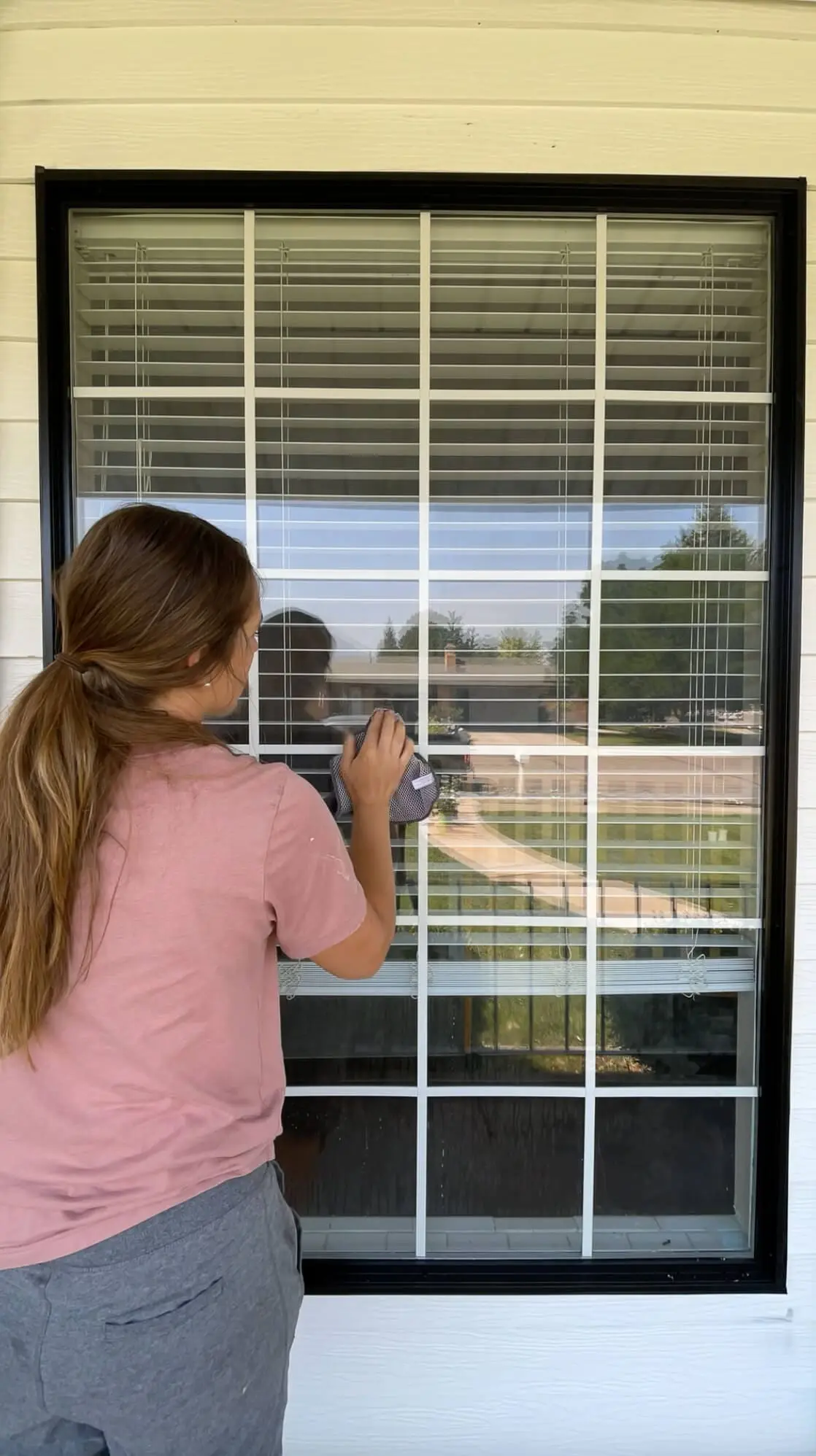 Woman wiping down a window with white grids using a microfiber cloth before a DIY window update.